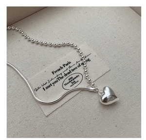 Close-up of S925 sterling silver heart pendant necklace on textured linen background