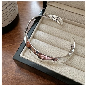 Détail d'un bracelet manchette en argent S925 avec textures ondulées et fini poli