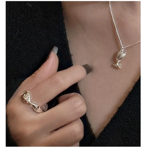Detail of silver wavy texture ring and miniature goblet pendant necklace on model