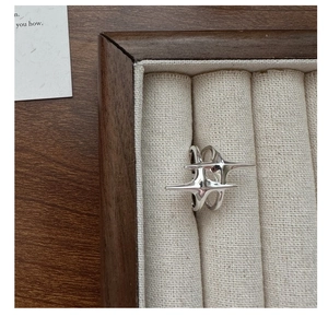 Détail macro d'une bague étoile en argent S925 dans un écrin en velours sur bois
