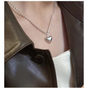 Detailed macro of a silver heart pendant featuring a unique beaded chain splice design