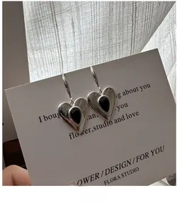 Detailed view of S925 silver heart earrings with black agate on a white display card