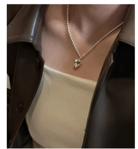 Detail of S925 silver heart necklace with asymmetric bead and snake chain on neck