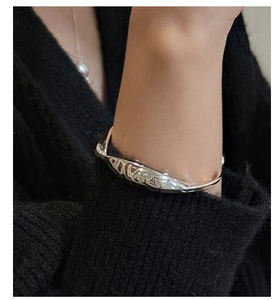 Gros plan sur un bracelet vague en argent S925 poli avec texture de métal liquide fluide