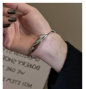 Gros plan d'un bracelet minimaliste en argent fin S925 avec texture de métal liquide au poignet