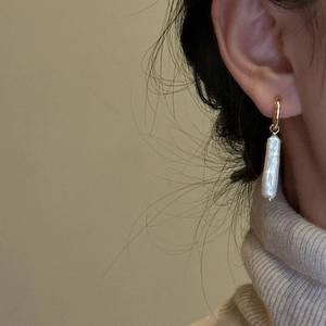 Elegant S925 silver gold hoop earrings with baroque pearls worn by a model in soft light
