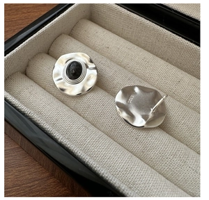Close-up of S925 silver earrings with pleated texture and black natural stone inlay