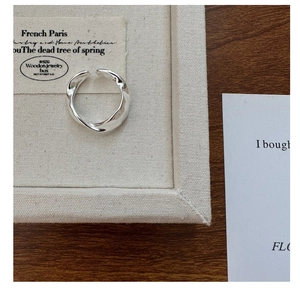 Top view of a minimalist S925 sterling silver wavy twisted ring on a textured fabric