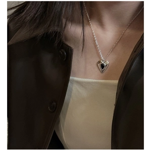 Detail of silver heart necklace with black stone on model for a modern look