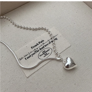Macro detail of S925 silver heart pendant necklace with dual-style bead and snake chain