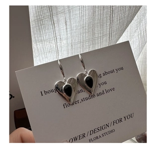 Macro detail of S925 silver heart earring with black onyx inlay on elegant white card