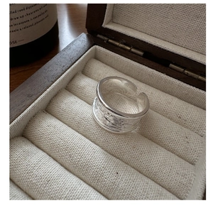 Gros plan d'une bague en argent S925 avec texture unique dans une boîte à bijoux en bois