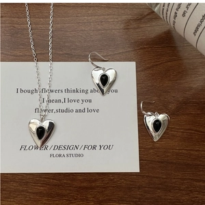 Macro shot of S925 silver heart necklaces and earrings set with black agate stones