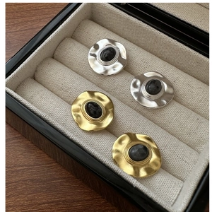 Detailed shot of S925 silver and gold hammered earrings with natural black stone inlay