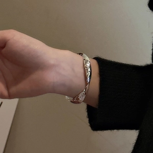 Bracelet jonc vague en argent S925 avec texture martelée porté sur un poignet de femme
