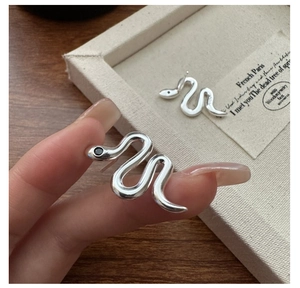 Close-up of S925 sterling silver snake earrings with black gemstones on fabric jewelry box