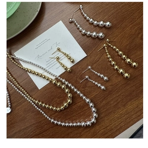 S925 sterling silver gradient bead necklace and earrings set on a wooden surface