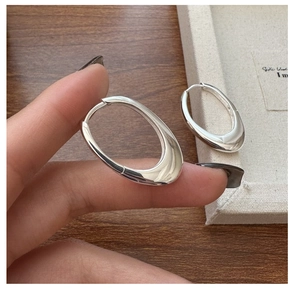 Macro shot of S925 sterling silver oval hoop earrings with a fluid irregular design