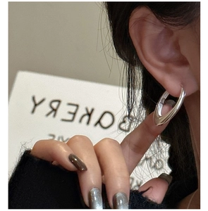 Close-up of minimalist S925 sterling silver oval hoop earring worn on ear