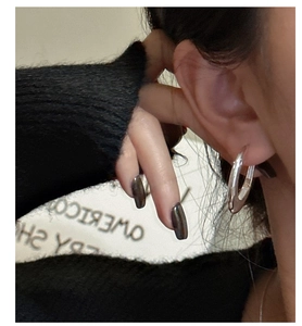 Close-up of minimalist S925 sterling silver oval hoop earrings worn on female ear