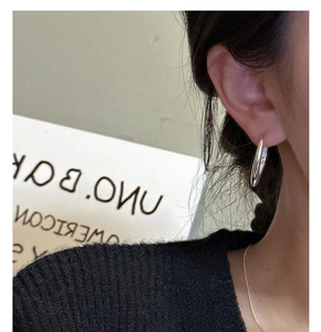 Detail view of model wearing S925 sterling silver oval hoop earrings and thin necklace