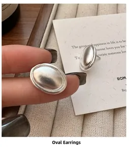 Gros plan détaillé de la texture mate brossée des boucles d'oreilles ovales en argent S925