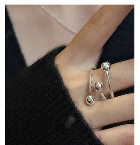 Vue macro d'une bague spirale en argent avec perles polies portée sur fond noir sombre