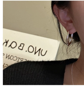 Close-up of minimalist S925 sterling silver oval hoop earring worn on a female model