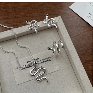 Macro shot of silver snake jewelry set with black stone accents on a textured tray