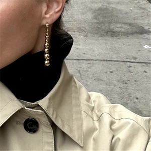 Minimalist S925 silver gold bead drop earrings worn by a model in a street style setting