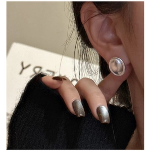 Vue macro de boucles d'oreilles ovales mates en argent sterling S925 sur modèle