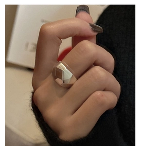 Detailed close-up of a wide polished S925 sterling silver ring with geometric facets