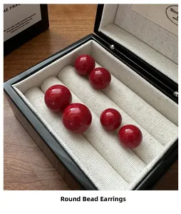 Close-up of three pairs of glossy red bead earrings in a premium black jewelry box
