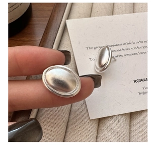 Gros plan de boucles d'oreilles ovales en argent mat avec une texture brossée élégante