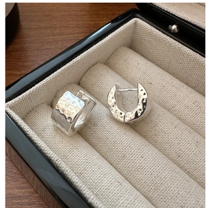 Macro shot of silver S925 earrings with handcrafted hammered texture in a jewelry box