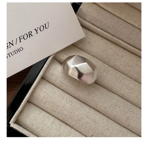 Macro view of wide geometric matte silver ring displayed in a luxury velvet jewelry box