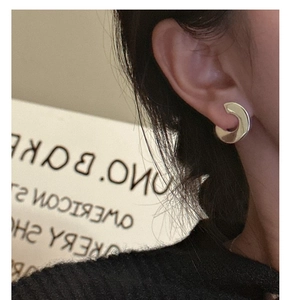 Close-up of a model wearing minimalist golden C-shaped sterling silver hoop earrings