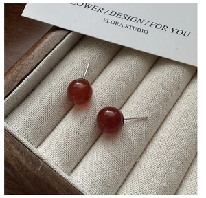 Macro shot of red agate stud earrings with S925 silver posts in a wooden jewelry box