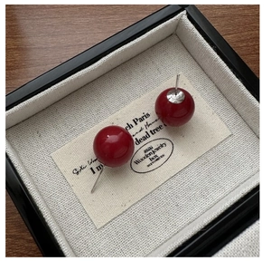 Macro shot of minimalist S925 sterling silver red bead earrings in a jewelry box