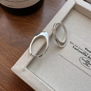 Polished S925 sterling silver oval hoop earrings displayed on a minimalist jewelry tray