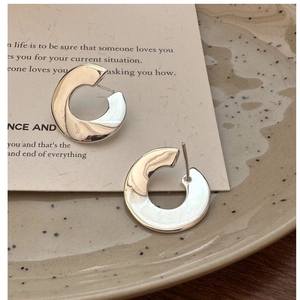 Macro shot of silver C-shaped lava textured earrings on a ceramic dish background