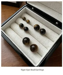 Detailed comparison of four sizes of sphere tiger eye stud earrings in a jewelry box