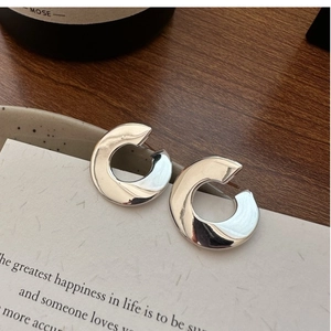 Close-up of C-shaped polished S925 sterling silver hoop earrings on a textured card