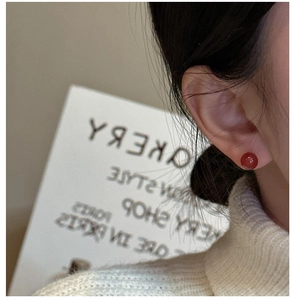 Detailed close-up of a red agate stud earring on a model for a minimalist style