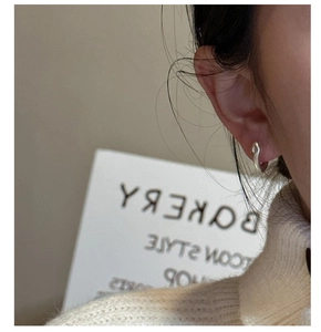 Gros plan d'une boucle d'oreille en argent S925 en forme de C sur l'oreille du mannequin