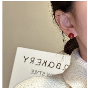 Close-up of a deep red round agate stud earring worn on ear with minimalist S925 silver base