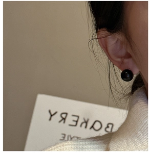 Close-up of minimalist black agate stud earrings shown on a model for a vintage look