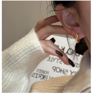 Gros plan de boucles d'oreilles dorées en forme de C portées par un mannequin chic