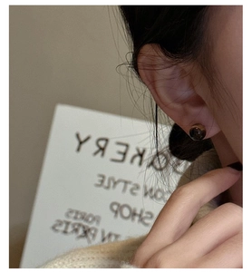 Detailed close-up of a vintage round brown tiger eye stud earring worn on a model
