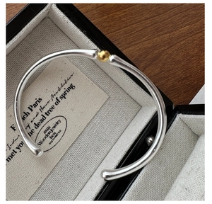 Vue détaillée du bracelet jonc argenté avec perle dorée dans son coffret à bijoux